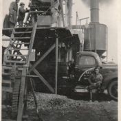 Kenteken: A 36445; Mient Plantinga op de treeplank van de Fargo truck waar asfalt in wordt geladen voor de wegenbouw, ca. 1950, foto: archief PAX