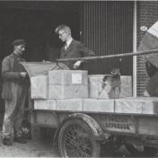 Kenteken: A 29007; Motorbakfiets, J. Eshuis in gesprek met de expediteur, A. Hut laadt de pakken papier in, foto: Lijnco, 1936-1986 (1769-12040)
