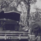 Kenteken: A 29223; Kaiser Frazer met open motorkap en G. W. J. Meijer, foto: still uit de film "Reis personeel tentoonstelling", Groothuis, 1953, coll. GrA (2209-4524)