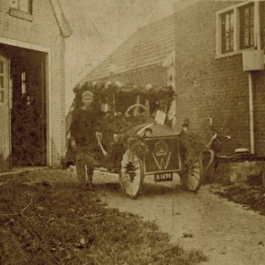 Kenteken: A 1898; Versierde auto met bloemen en koninklijke "W" op de grill ter gelegenheid van Koninginnedag, met onbekend jongetje, ca. 1916, foto: J.M.M. Geling