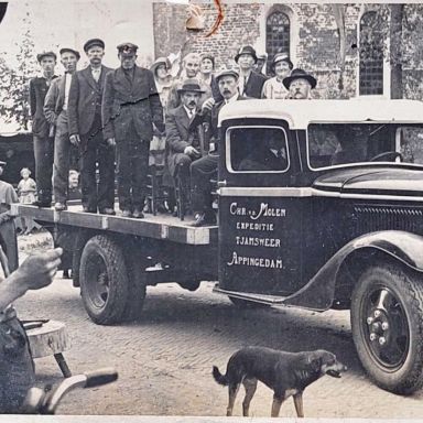 Kenteken: A 21792; Mensen poseren in de laadbak van de Ford V8 vrachtwagen voor het Meestershuis naast de kerk te Wirdum, Groningen, waarschijnlijk t.g.v. een schoolfeest, 1935, foto: H. de Wilde