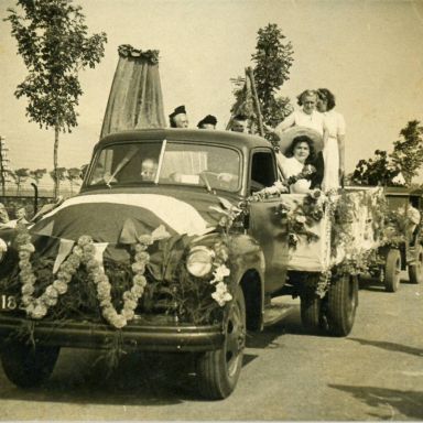 Kenteken: A 41828; Loppersum, Parallelweg,  Jan Balkema met naast zich zoon Hayo in de cabine van de feestelijk versierde Chevrolet vrachtwagen. Voor op de auto rechts Annie van der Laan; Fotograaf: W. F. Pastoor