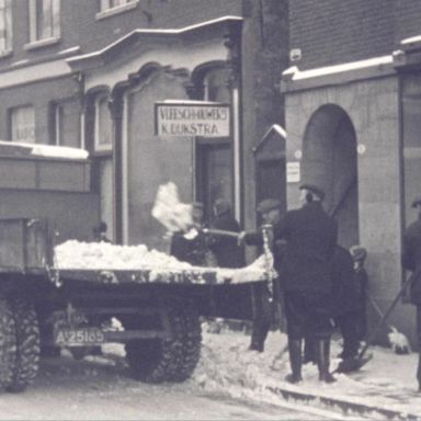 Kenteken: A 25185; Laadbak Ford V8 wordt vol geschept met sneeuw op de Nieuweweg, foto: still uit de film "De Groningsche reinigingsdienst voorheen en thans", C.R. Tiddens, 1936-1949 coll. GrA (2209-AV0061)