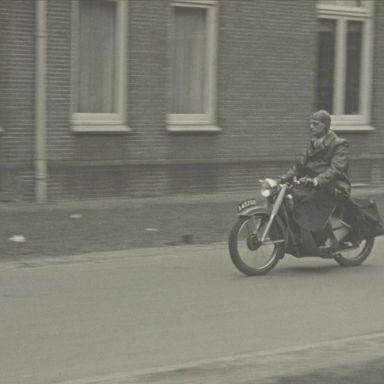 Kenteken: A 45298; Dokter van den Berg op zijn JAWA bij het Academisch Ziekenhuis in Groningen, foto: still uit de film "Een dag in de chirurgische kliniek", Foto-kino Wedema & Dijk, Bosman (regie), 1950 coll. GrA (2209-AV0472)